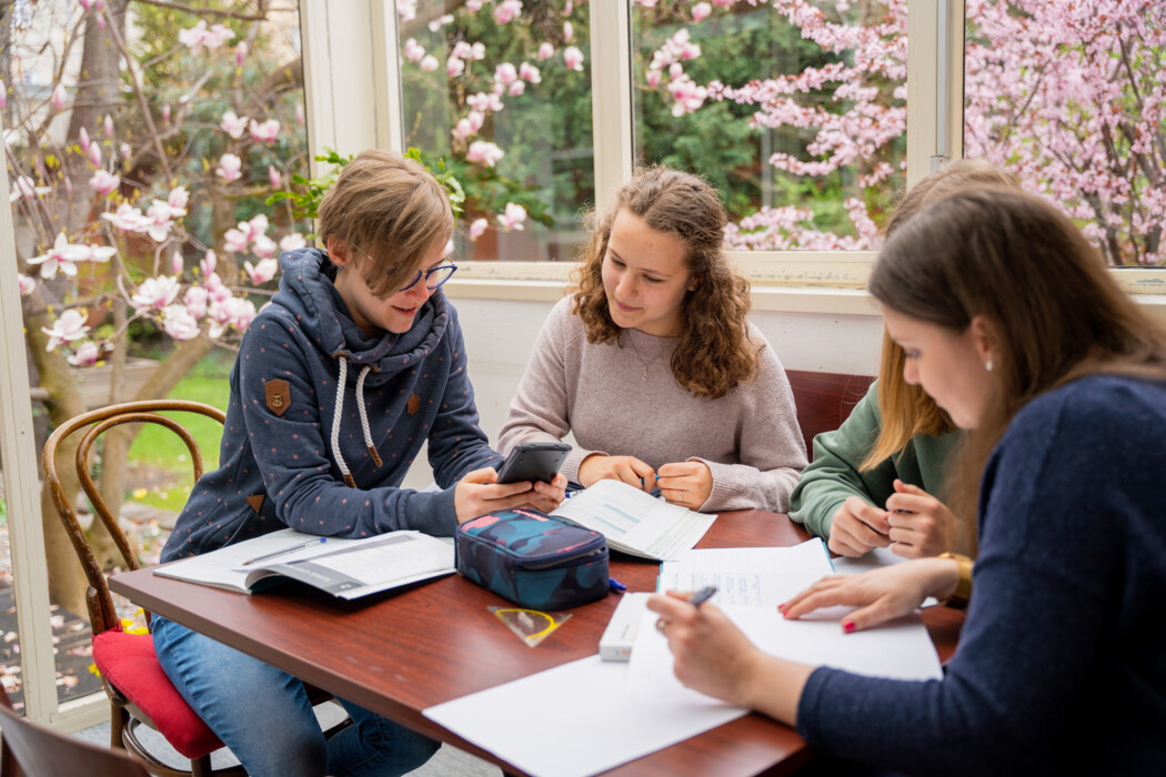 Mädchen und pädagogische Mitarbeiterinnen arbeiten in der Studierzeit an Hausübungen